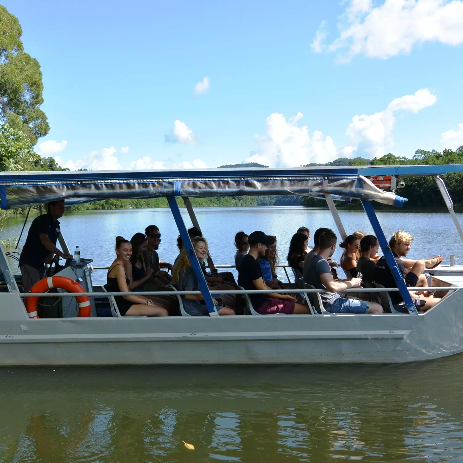 Guests on a covered river cruise boat looking for crocodiles