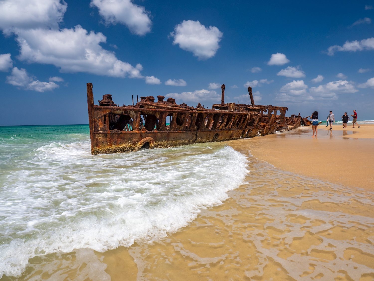 Rusty SS Maheno shipwreck in the surf on the beach