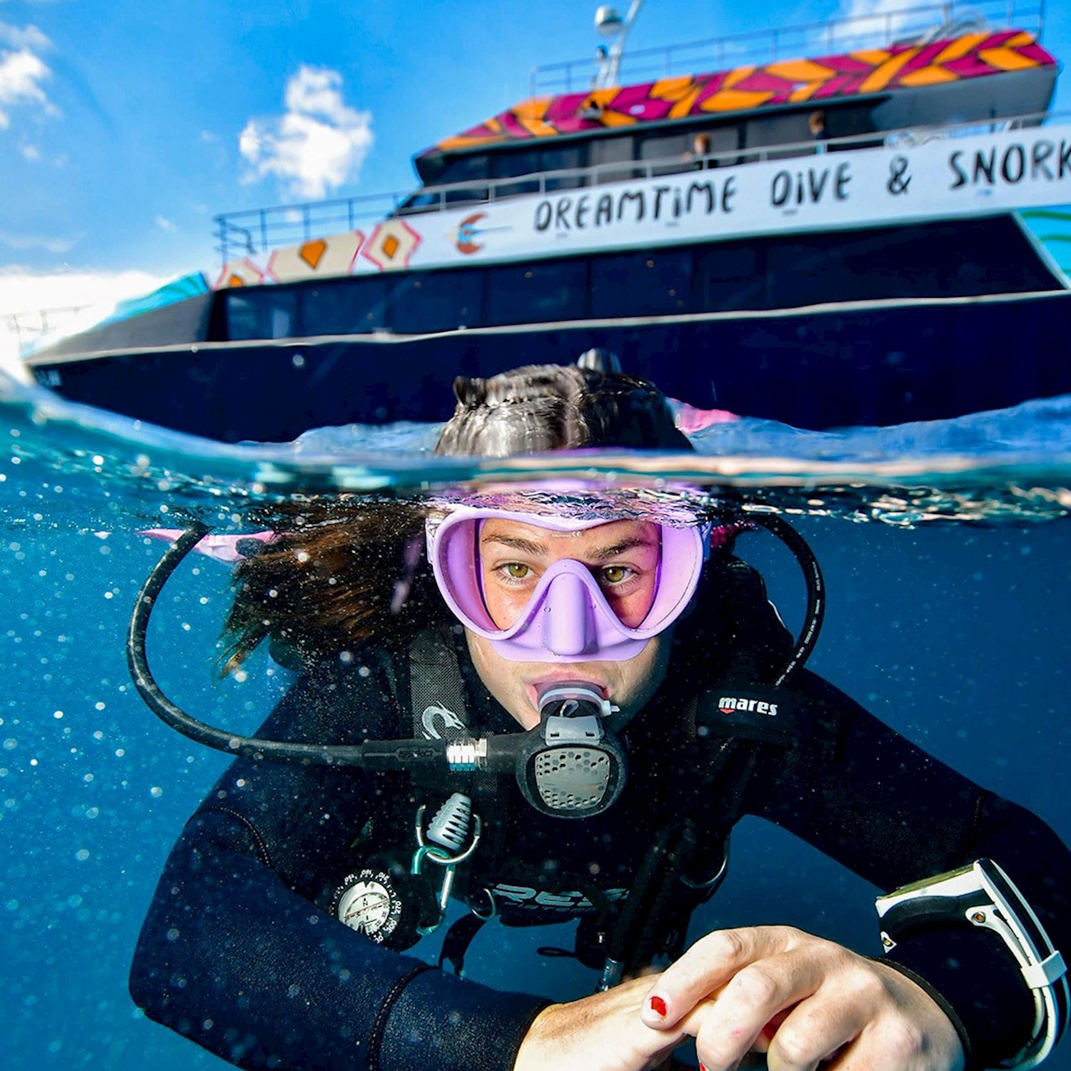 Snorkeller in a mask in the water in front of the Dreamtime Dive & Snorkel boat