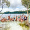 Group of travellers standing in the clear water of a K’gari lake