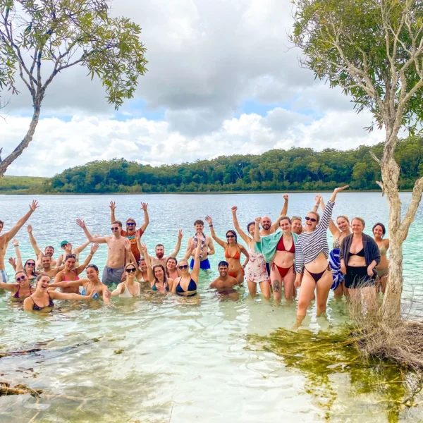 Group of travellers standing in the clear water of a K’gari lake