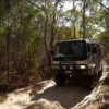4WD tour bus driving along a sandy bush track on Moreton Island