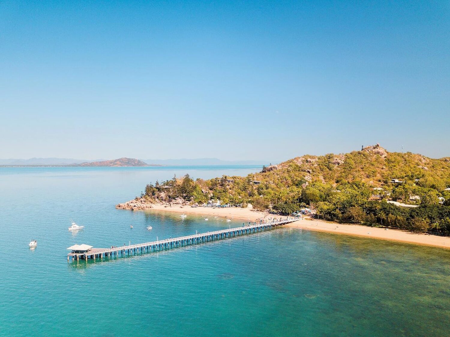 Long jetty reaching out over turquoise water from a tropical beach