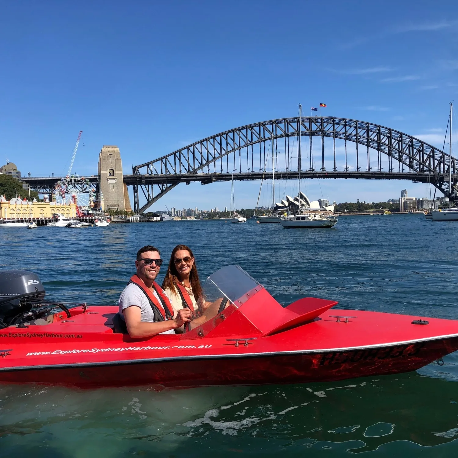 Red self-drive boat on the harbour with the Sydney Harbour Bridge behind